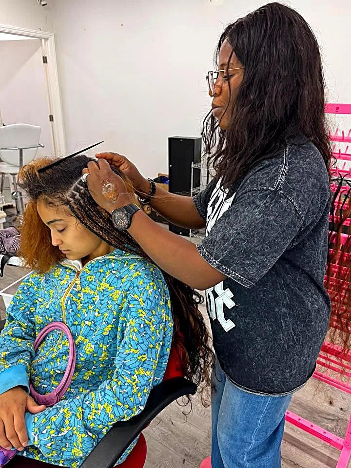 Stylist braiding a client's hair at Stella Braids and Hair Studio in Covina
